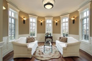 An elegant seating area with matching couches, crown molding, upgraded lighting, and new windows.