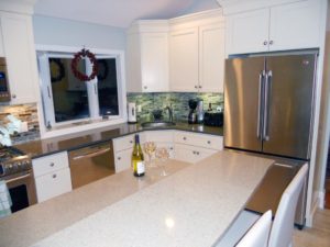 A beautifully remodeled kitchen with new stainless steel appliances and white cabinetry.