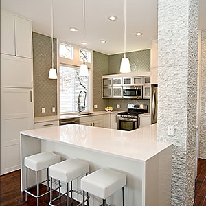 A beautiful, modern kitchen remodel featuring bar seating and attractive lighting.