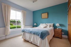 A lovely bedroom with blue statement wall and a big picture window